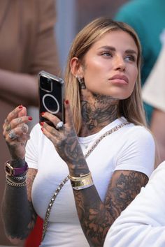 a woman with tattoos holding up her cell phone