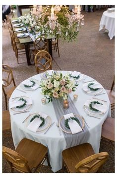 the table is set with white linens and greenery