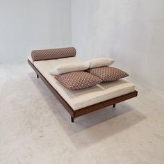 a bed with two pillows on top of it in the middle of an empty room