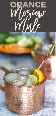 an orange moscow mule is garnished with limes and lemon wedges in a copper mug