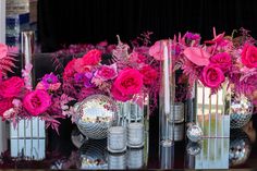 pink flowers and mirrored vases on a table with mirror balls in the centerpiece