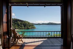 an open door leading to a balcony with a view of the water and mountains in the distance