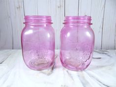 two pink mason jars sitting next to each other