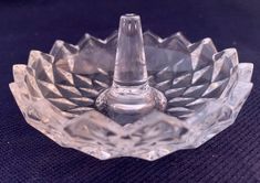 a clear glass bowl sitting on top of a blue cloth covered tablecloth with a candle holder in the middle