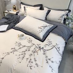 a bed with white and grey comforters on top of it