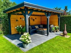 an outdoor living area with a couch and potted plants on the grass in front of it