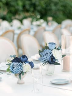 two vases filled with blue and white flowers sitting on top of a dining table