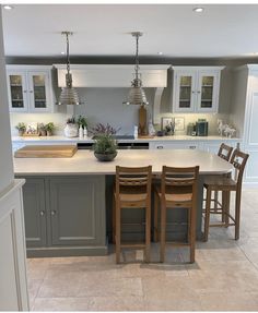 a large kitchen with an island in the middle and three chairs at the counter top