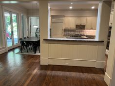 an empty kitchen and dining room with hardwood floors in the foreground, looking into the living room