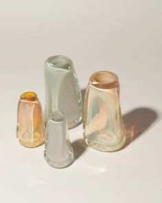 three glass vases sitting next to each other on a white surface with shadows from them