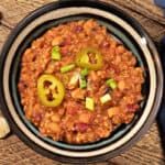 a bowl filled with chili and cheese on top of a wooden table