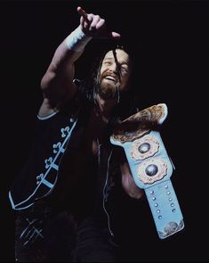 a man holding a skateboard in his right hand and wearing headphones on the other