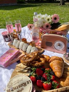 an assortment of pastries and desserts on a picnic table with pink flowers in the background