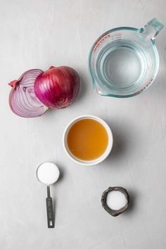 an onion, garlic, and other ingredients are on the counter next to a measuring cup