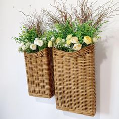 two wicker baskets with flowers in them hanging on the wall next to each other