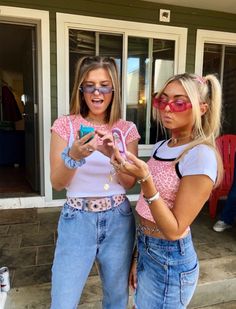 two women standing next to each other holding cell phones