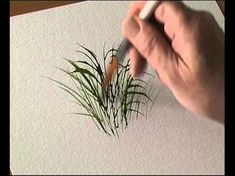 a hand holding a pen writing on a piece of paper with grass growing out of it