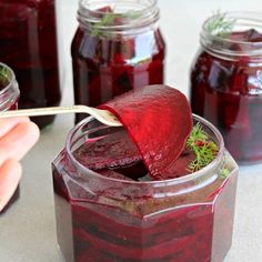 a jar filled with red liquid sitting on top of a table next to jars and spoons