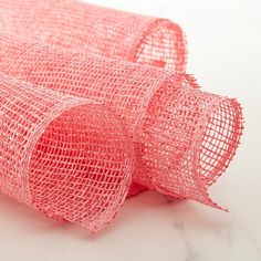 two rolls of pink mesh sitting on top of a white countertop next to each other