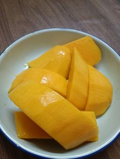 sliced mangoes in a white bowl on a wooden table