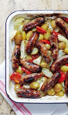 a casserole dish with sausages, onions and peppers