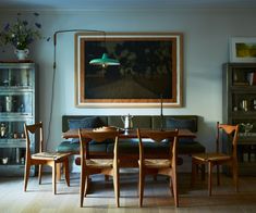 a dining room table with four chairs and a painting hanging on the wall above it