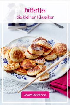 pancakes on a plate with chopsticks and powdered sugar in the middle, sitting on a lace tablecloth