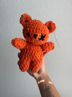 a hand holding an orange crocheted teddy bear