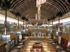 the inside of a shopping mall with palm trees and lights hanging from it's ceiling