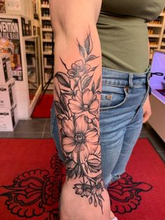 a woman's arm with flowers on it in a store display area, showing the tattoo design