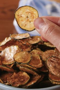 a person is picking up some kind of potato chips from a bowl on the table