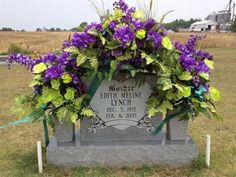 a grave with purple flowers and greenery on it