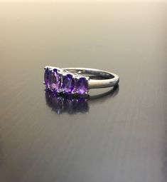 DeKara Designs Silver Metal- 14K White Gold, .583. Stones- 5 Natural Oval Amethyst, Center is 6.9 x 5 MM, Next To Center 6 x 4.3 MM, and last two are 4.9 x 3 MM. Size- Size- PLEASE ALLOW 5-7 WORKING DAYS FOR US TO SHIP OUT YOUR RING IN YOUR SPECIFIC SIZE AFTER TRANSACTION HAS BEEN COMPLETED PLEASE SPECIFY SIZE UPON CHECKOUT! An alternative to a diamond ring, here is timeless beautiful handmade 5 stone amethyst engagement ring. All the amethyst are fiery and set between 4 prongs. Very affordable Tanzanite Three Stone Wedding Jewelry, Purple Tanzanite Multi-stone Rings, Formal Purple Multi-stone Amethyst Ring, Classic Three Stone Amethyst Ring For Formal Occasions, Multi-stone Amethyst Jewelry Round Cut, Purple Multi-stone Amethyst Ring In Fine Jewelry Style, Elegant Purple Amethyst Ring With Marquise Cut, Purple Multi-stone Amethyst Ring Fine Jewelry, Fine Jewelry Purple Amethyst Multi-stone Ring