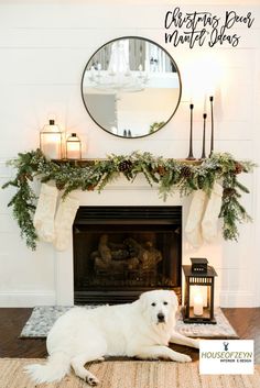 a white dog laying on the floor in front of a fireplace with stockings and candles