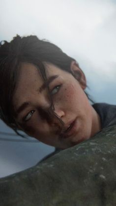 a young man with freckles on his face leaning against a rock