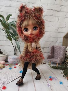 a doll is dressed up like a cat with red fur on it's head