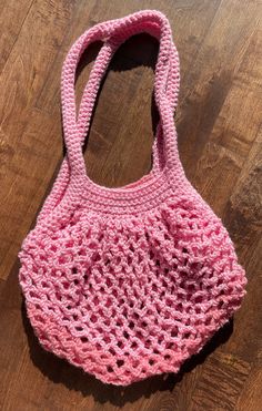 a pink crocheted bag sitting on top of a wooden floor