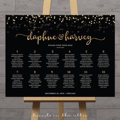 a black and gold wedding seating chart with glitter confetti on the top, in front of a wooden easer