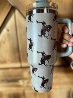 a person holding a cup with horses on it