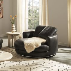 a living room with black leather chairs and a white rug on the floor in front of a window