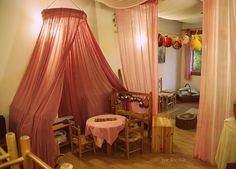 a pink canopy bed in a room with wooden floors