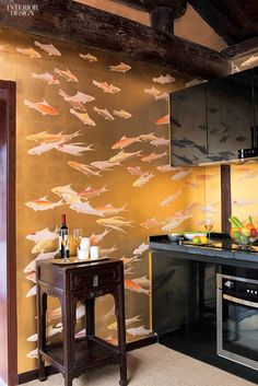 a kitchen area with an oven, microwave and table in front of a wallpapered fish pattern