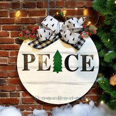 a wooden sign that says peace with a christmas tree on it next to a brick wall