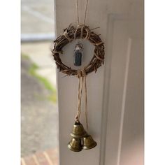 two bells hanging from the side of a door with twine around them and a wreath