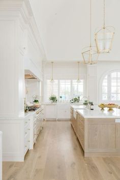 a large kitchen with white cabinets and wooden floors