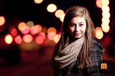 a young woman is standing in front of some boket lights and smiling at the camera