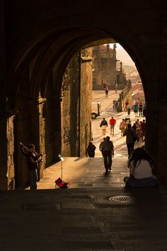 people are walking down an alley way in the city with archways and stone walls