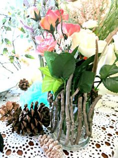 a vase filled with flowers sitting on top of a table next to a pine cone