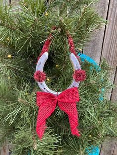 a christmas wreath hanging on the side of a wooden fence with red bows and pine cones