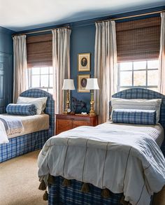 two beds in a bedroom with blue walls and plaid bed linens on the covers